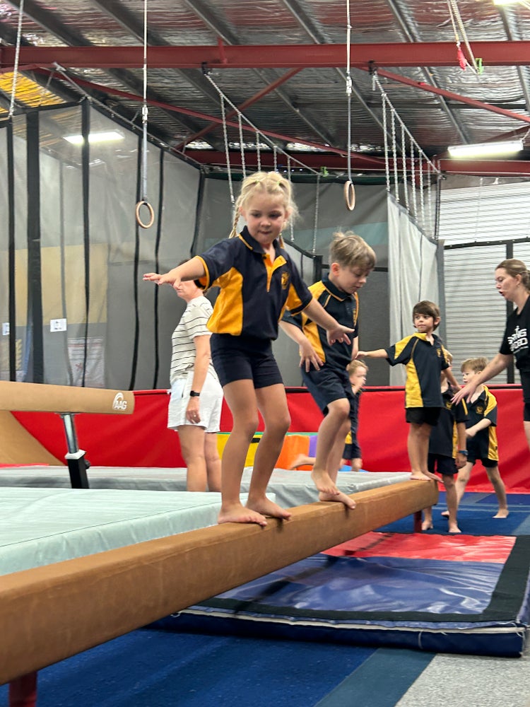K-2 students on a balance beam during a weekly Gymnastics PE sessions at Springloaded