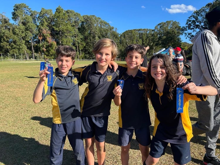 A group of Stge 2 boys with linked arms as they proudly displaying their athletic's ribbons